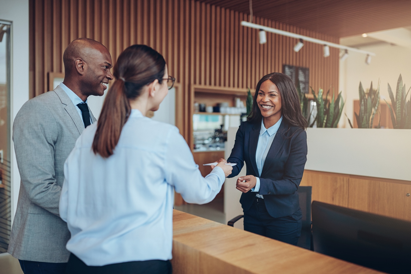 Smiling guests giving their check in information to hotel reception